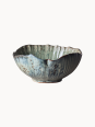 Rustykalna ceramiczna miska pokryta melanżowym jasnoniebieskim i beżowym szkliwem z brązowymi, nakrapianymi detalami na jednolitym białym tle.
